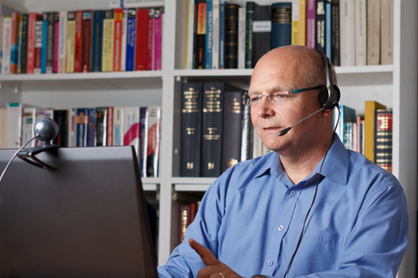 Man with headset and webcam attending a webinar in his home